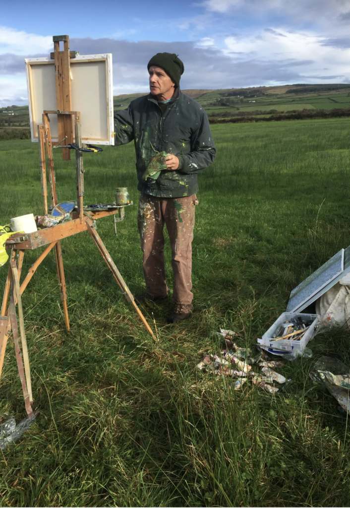 Andrew Wykes painting outdoors at his easel in a field