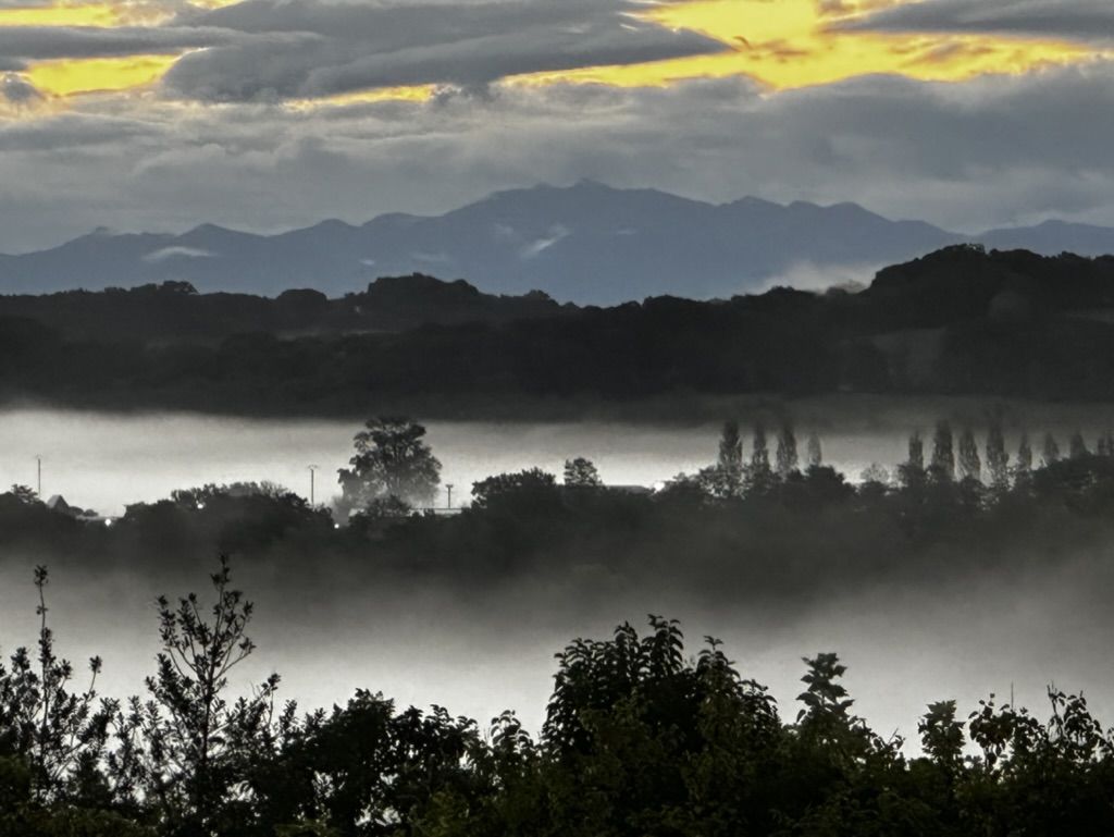 Morning mist in the valley with mountains behind